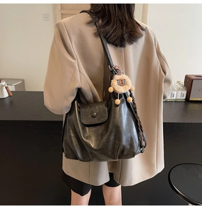 Detail view of large black faux leather tote bag with cute lion plush keychain accessory
