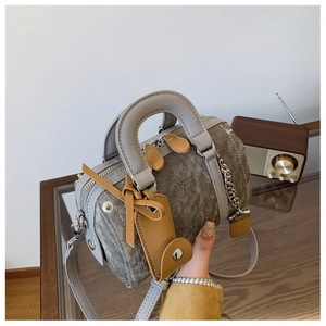 Detail of grey textured Boston bowling bag with leather handles and luggage tag