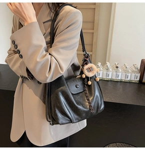 Detail of black faux leather tote with pleated texture and stylish plush lion charm