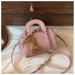 Close-up of pink Boston bag showing leather texture, brand embossing and hardware details