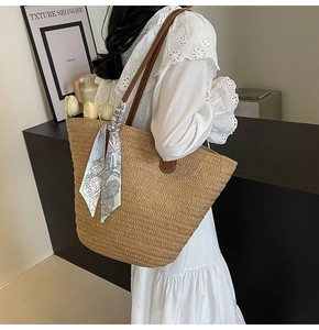 Detail of straw woven tote bag featuring floral silk scarf and brown leather handle strap