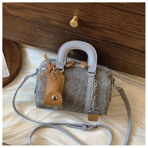 Detail of taupe denim Boston bag with light blue-grey leather handles and silver chain
