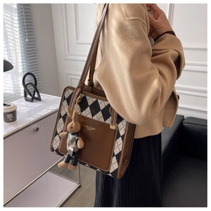 Detail of argyle canvas tote bag with brown leather pocket and plush bunny charm