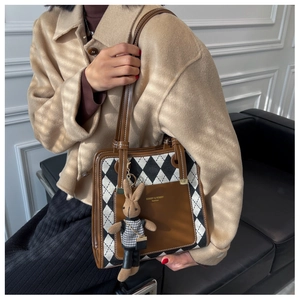 Detail of vintage argyle tote bag with brand logo and cute bunny doll charm accessory