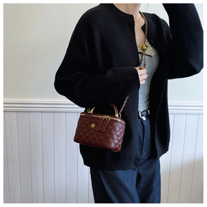 Detail of burgundy quilted leather vanity bag with gold flower buckle and chain strap