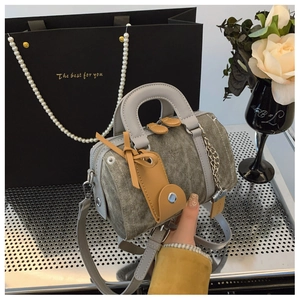 Detail of vintage grey denim Boston bag with leather handles and metallic chain accent