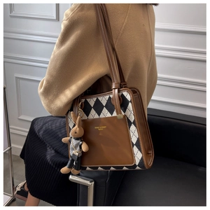 Detail of vintage quilted tote bag with brown leather trim and cute bunny charm on model