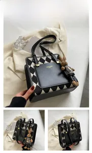 Detail of black quilted tote bag with gold logo plaque and cute bunny doll accessory