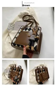 Detail view of the brown leather and argyle tote bag featuring a cute rabbit charm accessory