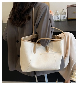 Détail du sac cabas en cuir blanc cassé avec anses marron et logo pour le quotidien
