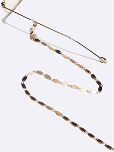 Detail of gold metal eyewear chain with oval discs and adjustable silicone loops