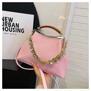 Detail of pink woven handbag featuring gold frame and resin handle with chain strap