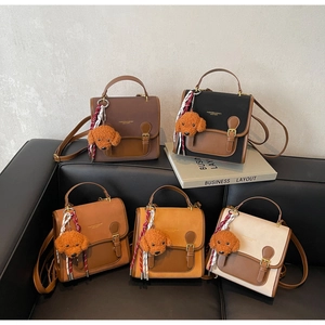 Detail of five vintage-style flap bags in various colors with cute plush dog charms