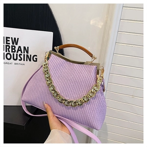 Detail view of purple woven handbag featuring wooden handle and decorative gold chain