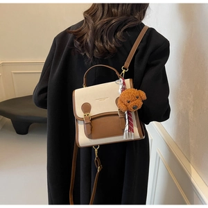 Detail of canvas and brown leather crossbody bag with fashion text and dog charm