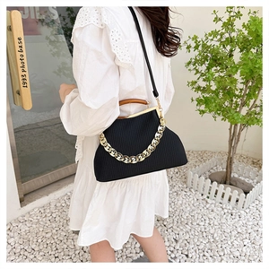 Detail of black textured evening bag featuring vintage wooden handle and gold chain