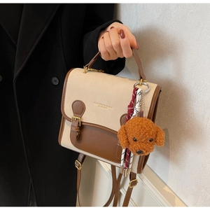 Detail of retro color-block backpack with gold logo and plush teddy bear pendant