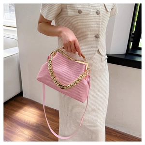 Close-up of pink woven evening bag featuring gold metal frame and luxury diamond chain