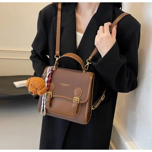 Detail of vintage brown leather backpack with gold buckle and cute dog charm accessory