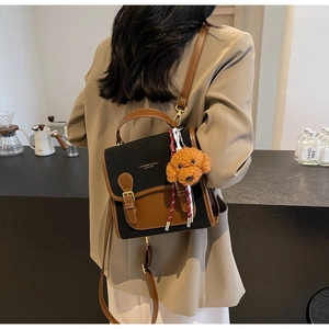 Detail view of contrast leather backpack with luxury lettering and cute dog charm pendant