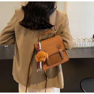 Close-up of brown vintage PU leather crossbody bag with a cute plush dog charm
