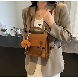 Detail of vintage brown leather handbag with teddy charm and elegant gold lettering