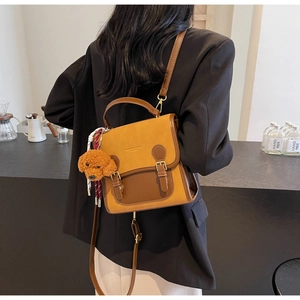 Detail of vintage brown leather crossbody bag with teddy charm and double buckle straps