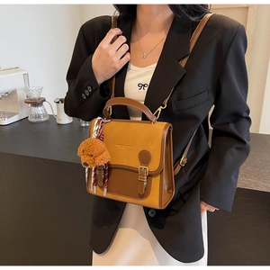 Close-up of retro color-block handbag with leather strap and cute plush dog charm