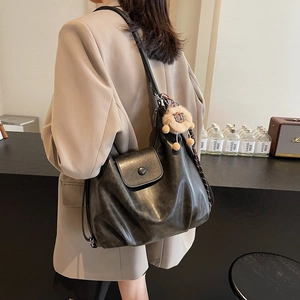 Large dark grey soft PU leather tote bag with lion pendant worn by model in a cafe