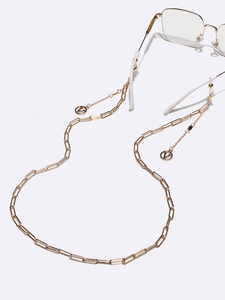 Detail showing gold chain with rectangular links and V-shaped letter charms on glasses