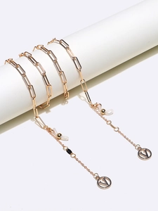 Close-up of golden paperclip chain eyeglass strap with V-letter pendant and lobster clasps