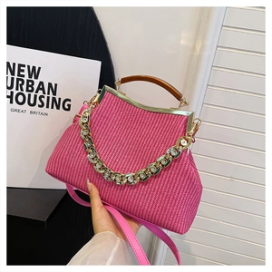Fuchsia woven handbag with retro wooden handle and gold chain strap in hand