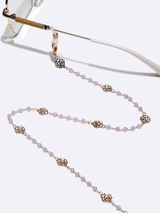 Detail der Brillenkette in Gold mit lila Perlen und hohlen Rosenanhängern für Damen