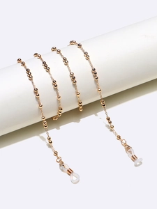 Detail of golden beaded glasses chain with silicone loops on minimalist pedestal