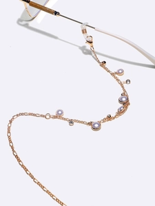 Chaîne de lunettes dorée avec perles lavande et strass sur monture de lunettes blanche