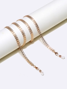 Detail view of golden eyewear chain featuring hollow leaf charms and silicone loops