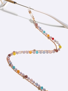 Detail of colorful crystal beads on a double-layer gold chain for glasses or masks