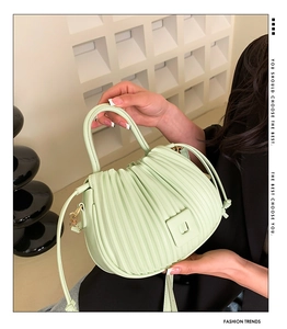 Detail of light green ruched texture and round handle on a fashion crossbody bucket bag