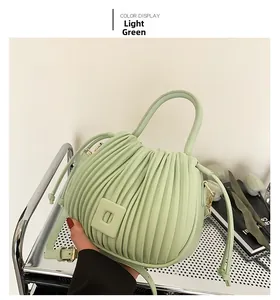 Detail of light green ruched bucket bag with metallic buckle and adjustable strap