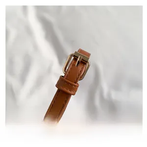 Detail of adjustable caramel leather shoulder strap with a polished gold metal buckle