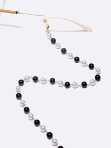 Detalle de cadena para gafas con perlas blancas y negras de 8 mm y cierres metálicos dorados