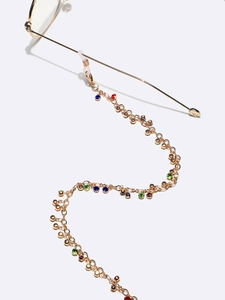 Dettaglio catena per occhiali dorata con strass colorati e anelli in gomma morbida
