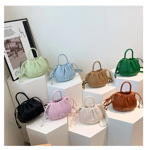 Multiple colors of pleated bucket bags displayed on geometric stands with drawstring closure