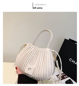 Detail of cream pleated handbag featuring vertical texture and square clasp