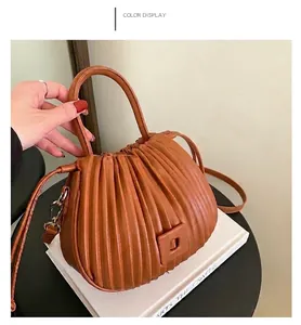 Brown pleated cloud handbag on artistic books with golden hardware and textured finish