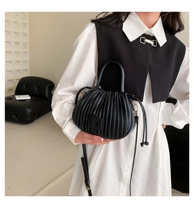 Detail view of black pleated dumpling bag with textured vegan leather and top handle