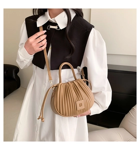 Close-up of khaki pleated bucket bag with D logo detail and stylish drawstring tassel