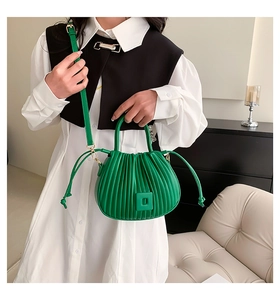 Detail of green ruched bucket bag showing vibrant pleated texture and shoulder strap