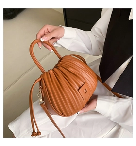 Detailed view of the pleated texture and golden hardware on the caramel bucket bag