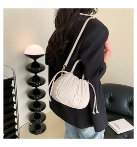 Close-up of pleated cream bucket bag with drawstring detail and adjustable strap